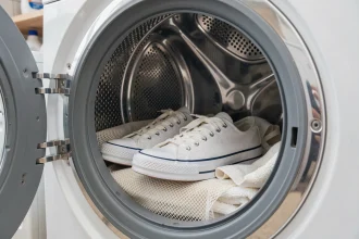 Paire de converses blanches placées dans un lave-linge avec un filet de lavage pour un nettoyage en machine sans dommage