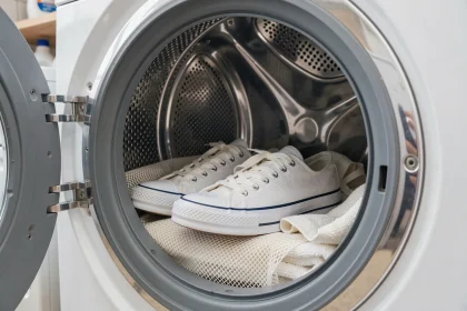 Paire de converses blanches placées dans un lave-linge avec un filet de lavage pour un nettoyage en machine sans dommage